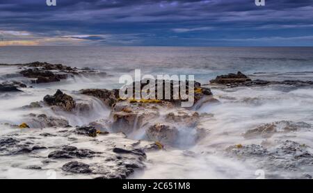 Onde oceaniche che riempia il pozzo di lava di Pele vicino a Wawaloli Beach sulla Big Island delle Hawaii, Stati Uniti. Foto Stock