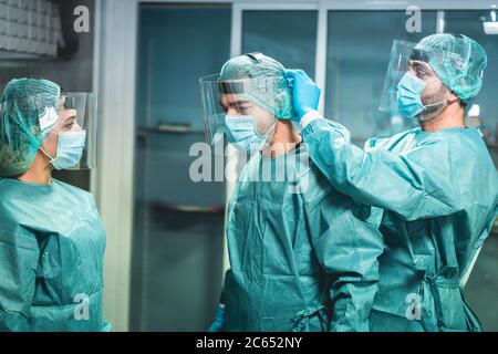 Medici e infermieri si preparano a lavorare in ospedale per l'intervento chirurgico durante l'epidemia di coronavirus pandemic - operatori medici che si vestono all'interno c Foto Stock
