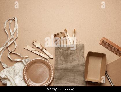 borsa in tessuto bianco e stoviglie monouso di carta marrone artigianale su sfondo di legno marrone. Vista dall'alto, concetto di rifiuto della plastica, zero sprechi Foto Stock