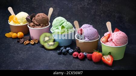 Vari gelati colorati in tazza di carta su sfondo rustico scuro Foto Stock