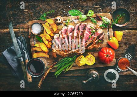 Carne alla griglia, ​​tomahawk bistecca di manzo affettata con spezie, patatine fritte e verdure su sfondo rustico Foto Stock