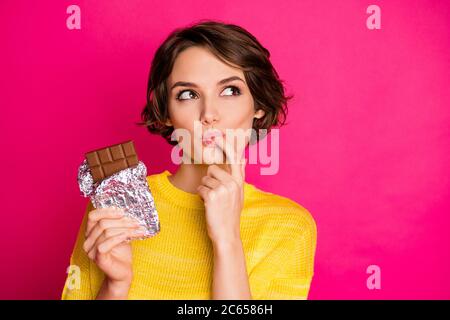 Primo piano-in su ritratto di lei bella-osservante attraente grazioso affascinante sognante ragazza gustando cioccolato scuro cacao isolato su luminoso Foto Stock