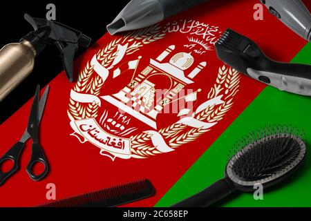 Bandiera Afghanistan con utensili per il taglio dei capelli. Pettini, forbici e utensili per parrucchieri in un salone di bellezza su sfondo nazionale in legno. Foto Stock