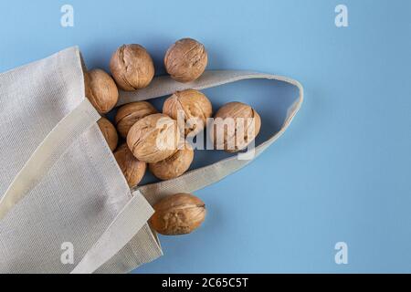 Noci in sacchetto di cotone su sfondo blu. Naturale biologico sano e vegan concetto di cibo. Disposizione piatta, vista dall'alto con spazio per la copia Foto Stock