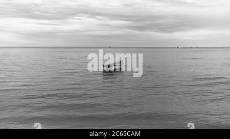 Una barca solitaria sul mare in stile monocromatico, Hua Hin Thailandia Foto Stock