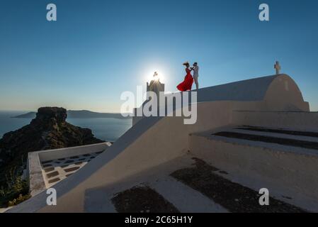 Un brindisi al tramonto sul tetto del piccolo chuch di Agios Georgios che si affaccia sul mare dell'Isola di Santorini, Imerovigli, Grecia Foto Stock