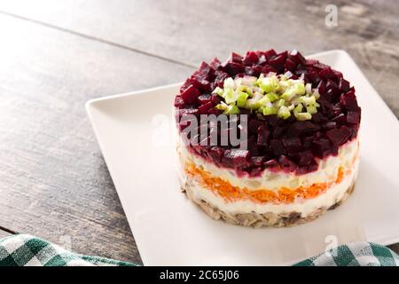 Insalata tradizionale russa di aringhe con barbabietole e carote su tavolo di legno Foto Stock