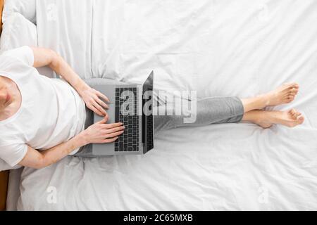 Donna di successo seduta a letto che lavora su un computer portatile Foto Stock