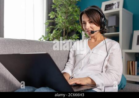 Bella donna in cuffia con videochiamata sul computer portatile Foto Stock