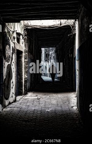 L'uomo cammina attraverso un vicolo scuro a Essaouira Foto Stock