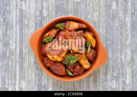 Pollo fritto o pollo fritto kabab che è ben guarnito con foglie di curry in una terracotta con sfondo grigio Foto Stock