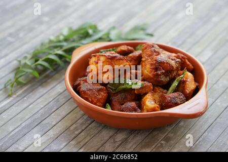 Pollo fritto o pollo fritto kabab che è ben guarnito con foglie di curry in una padella nera con sfondo grigio o prodotti di terra Foto Stock