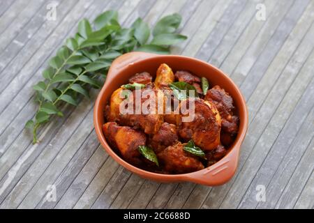 Pollo fritto o pollo fritto kabab che è ben guarnito con foglie di curry in una padella nera con sfondo grigio o prodotti di terra Foto Stock