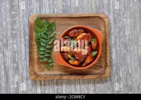 Pollo fritto o pollo fritto kabab che è ben guarnito con foglie di curry in una padella nera con sfondo grigio o prodotti di terra Foto Stock