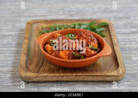 Pollo fritto o pollo fritto kabab che è ben guarnito con foglie di curry in una padella nera con sfondo grigio o prodotti di terra Foto Stock