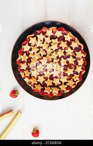 Torta di fragole e rabarbaro decorata con stelle su tavola bianca, vista dall'alto Foto Stock