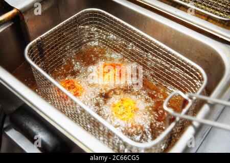 Friggere un piatto in cucina fast food, cibi spazzatura grassa, tonato Foto Stock