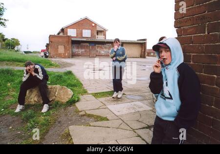 Bambini adolescenti che si aggirano intorno al club giovanile; run down council housing station; Bradford UK Foto Stock