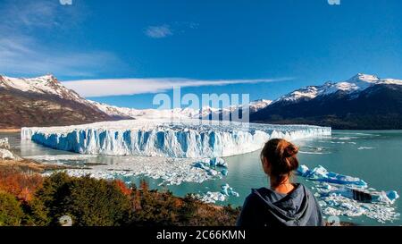 Persona di fronte al ghiacciaio Perito Moreno, paesaggio autunnale in primo piano e galleggianti di ghiaccio in acqua, El Calafate, Argentina Foto Stock