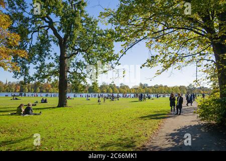La domenica di autunno è soleggiata presso il lago Serpentine di Hyde Park, Londra, per una pausa dalla vita lavorativa Foto Stock