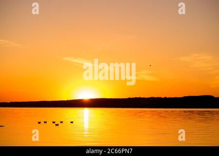 sei origami sotto forma di barche navigano sul lago al tramonto in serata. Foto Stock