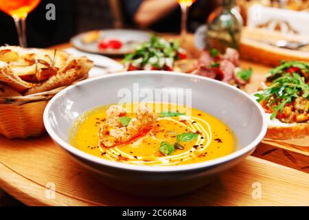 Piatto profondo con zuppa di zucca e un altro cibo, cena italiana in un ristorante, tonato Foto Stock