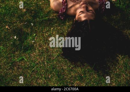 giovane donna sdraiata sull'erba con lunghi capelli lisci Foto Stock