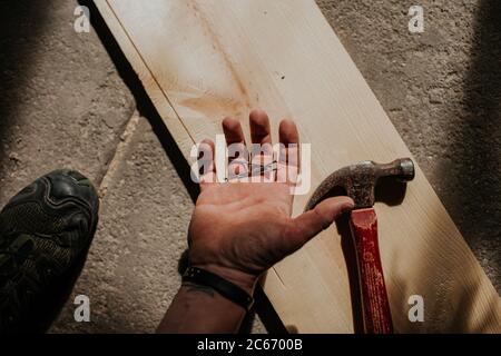 colpo di testa di uomo che tiene unghie in mano Foto Stock