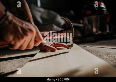 Uomo che martellano il chiodo a bordo Foto Stock