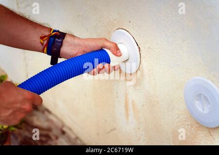 Persona che pulisce e clorurando la piscina in un caldo pomeriggio estivo, sta facendo funzionare il pulitore e aggiungendo polvere di cloro Foto Stock