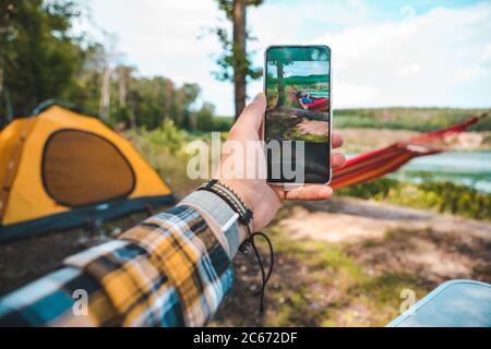 uomo che prende la foto del telefono delle donne che posano sull'amaca Foto Stock