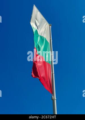 Bandiera bulgara che sventola su sfondo blu. La posizione è Obzor, Bulgaria. Bandiera della Bulgaria contro il cielo limpido. Foto Stock