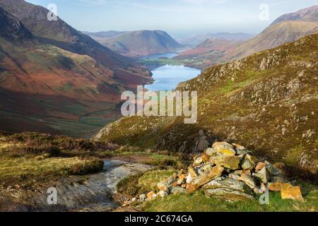 Il sole presto che fornì una luce calda su un cairn vicino a Haystacks cadde, con acqua di Buttermere e Crummock sullo sfondo. Lake District, Cumbria, Inghilterra Foto Stock