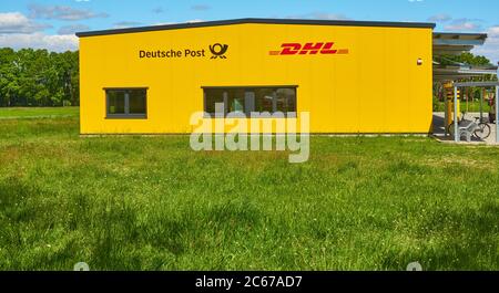 Gifhorn, Germania, 15 maggio 2020: Edificio giallo luminoso di una società di logistica tedesca dietro un campo verde, ufficio postale, distributore di pacchi Foto Stock