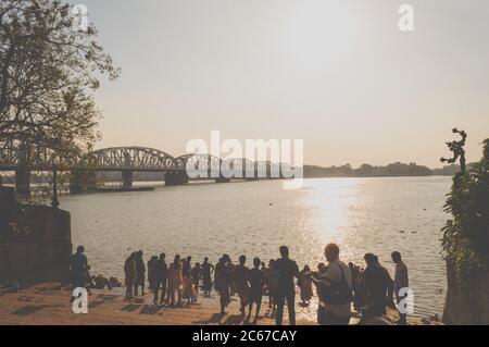 Dakshineswar Kali Mandir Tempio Ghat sulla riva di Holi Gange. Ora del tramonto. Gente affollata che fa rituali serali. Vista del sole con corrimano silhouette Foto Stock