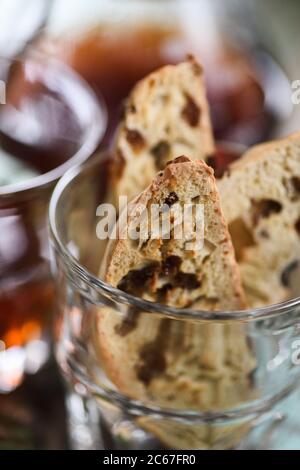 Primo piano di biscotti o cantucci tradizionali italiani fatti in casa con uvetta in vetro servita con caffè in primo piano Foto Stock