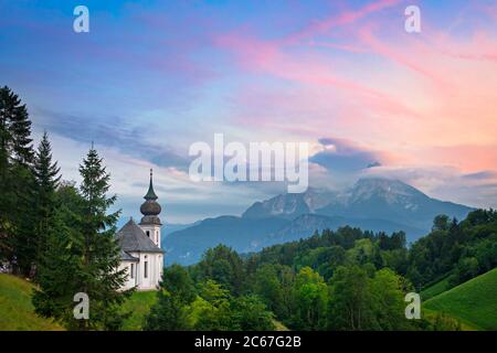 La chiesa Maria Gern con vista sul monte Watzmann nelle Alpi durante un colorato tramonto in una serata estiva a Berchtesgaden, Baviera, Germania. Foto Stock