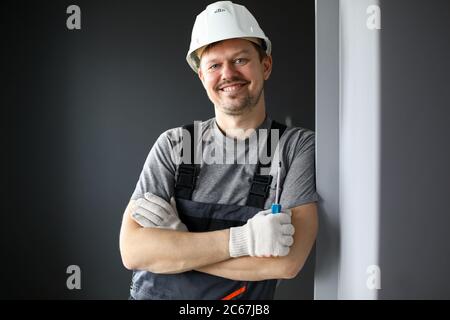 Maschio costruttore in tute e elmetto sorridente Foto Stock