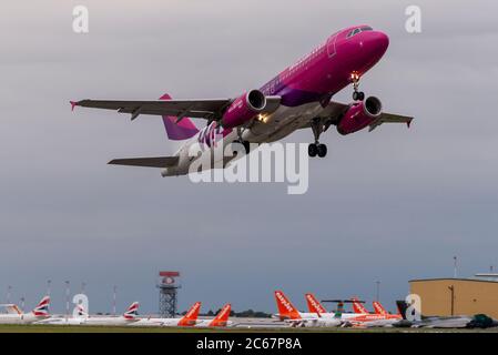 Aeroporto Southend di Londra, Essex, Regno Unito. 7 luglio 2020. Con easyJet che annunciava l'intenzione di chiudere la loro base a Southend, ci sono state alcune notizie positive per l'aeroporto, con Wizz Air che ha ripreso il servizio per Bucarest in Romania. La compagnia aerea ungherese è stata una delle numerose compagnie aeree che hanno utilizzato Southend prima del blocco COVID-19 per il coronavirus. La partenza come volo W63036, decollò alle 20:10 come qui sopra i molti aerei easyJet in eccedenza ancora immagazzinati a Southend Foto Stock