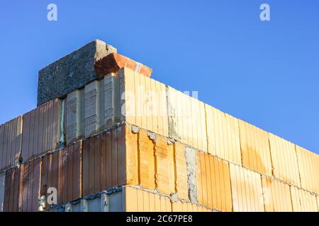 vista dell'angolo di un nuovo edificio, costruito da grandi blocchi su uno sfondo blu cielo Foto Stock