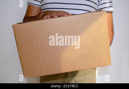 L'uomo sta tenendo in mano il pacco di consegna della scatola di cartone. Shopping online e consegna rapida. Uomo di consegna. Foto Stock