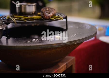 Lo chef prepara bistecche di manzo e asparagi alla griglia in giardino Foto Stock