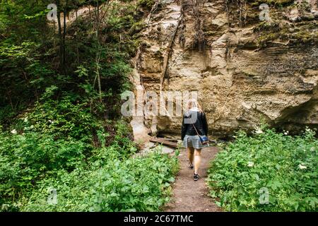 Donna persona che cammina sul sentiero escursionistico del canyon Hinni, scogliera fatta di una sabbia in Estonia. Võru. Foto Stock