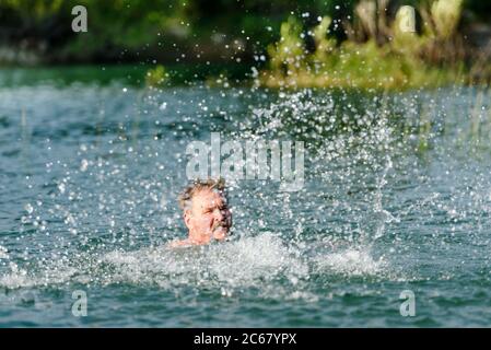 Un uomo bagna nel lago e fa spruzzi Foto Stock