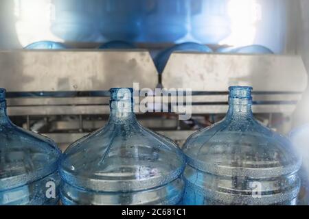 Bottiglie in PET o galloni di plastica sulla linea di produzione o nastro trasportatore in fabbrica di acqua per l'imbottigliamento di acqua potabile pura. Foto Stock