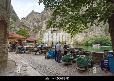 Al Matka Canyon, vicino a Skopje, mentre la sera presto si avvicina, la gente comincia a riunirsi per un pasto o una bevanda vicino alle acque calme del lago Matka. Foto Stock