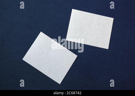 due biglietti di carta bianca su sfondo blu scuro con texture, modello aziendale messo a caso Foto Stock