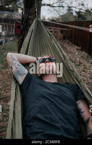 Verticale dell'uomo che si rilassa sull'amaca nel cortile Foto Stock