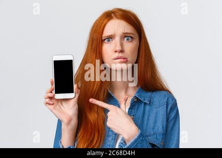 Preoccupato, insicura e allarmato ragazza cute redhead che chiede consiglio che hanno problemi di messaggistica con sconosciuto su dating app, non sapere che risposta Foto Stock