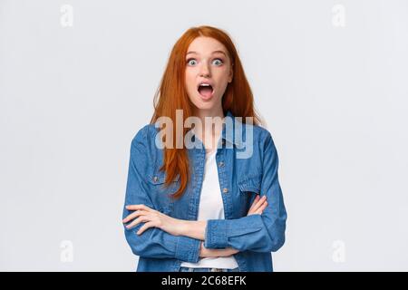 OMG, niente, incredibile. Impressionato e sorpreso, curiosa ragazza redhead cadere mascella dallo stupore, perdere il discorso, stellato stupito, in piedi Foto Stock